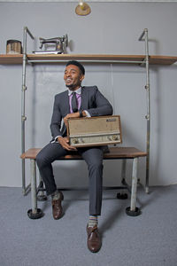 Full length of a smiling young man sitting at home