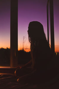 Side view of silhouette woman sitting against sky during sunset