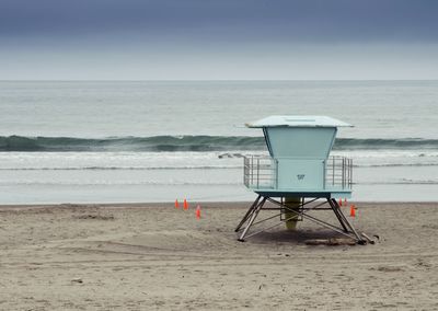 Lifeguard chair on beach against sky