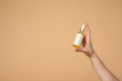 Close-up of woman hand against orange wall