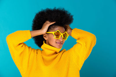 Portrait of smiling young woman against blue background