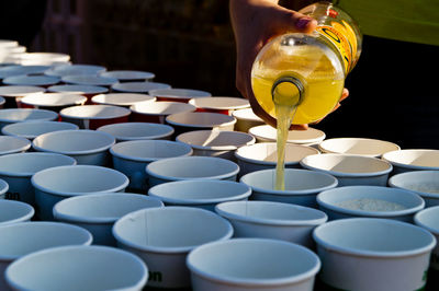 Cropped image of person pouring juice in disposable