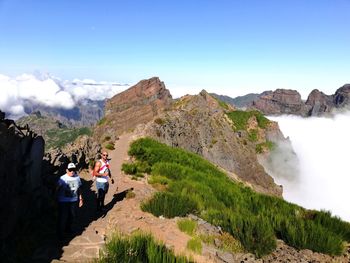 Rear view of people on mountain against sky