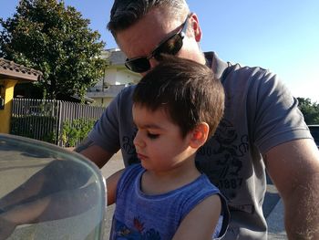 Father and son with daughter against sky