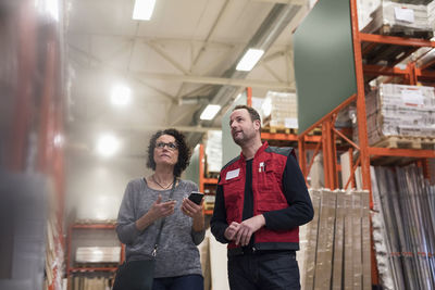 Customer holding smart phone while standing with salesman in hardware store