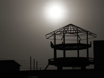 Silhouette hut by sea against sky during sunset