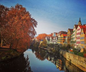 Canal amidst buildings against sky during autumn