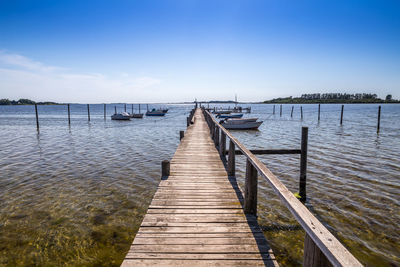 Wooden pier over lake against sky