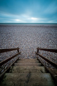 Staircase leading towards sea against sky