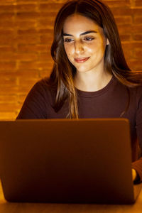 Young woman using laptop while sitting on table