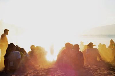 Rear view of group of people sitting on beach