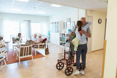 Young woman embracing grandfather during visit at nursing home