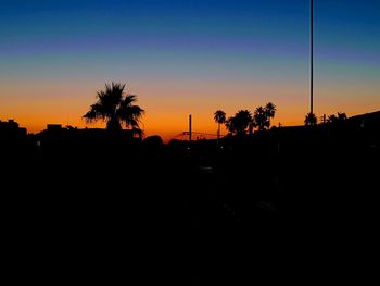 Silhouette palm trees against clear sky at sunset