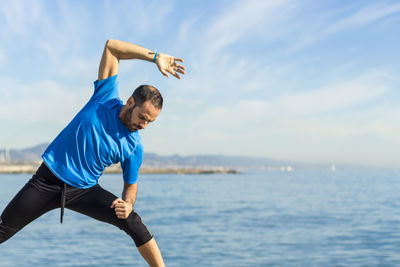 Man exercising against sea at beach