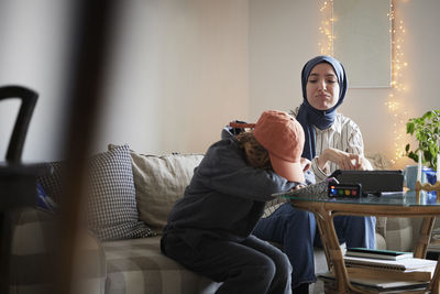 Mother wearing hijab helping tired son with add or adhd doing homework