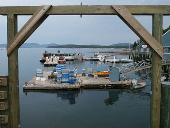 Crates and boats against sky at harbor