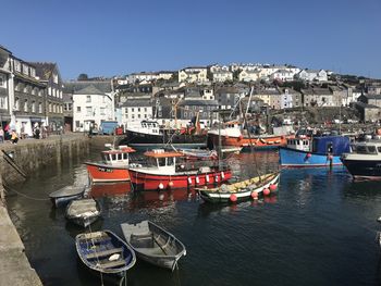 Boats moored in harbor against buildings in city