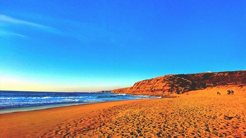 Scenic view of beach against blue sky