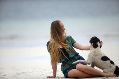 Rear view of woman with dog sitting on beach