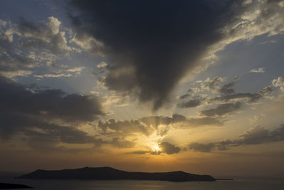 Scenic view of dramatic sky over silhouette mountains during sunset