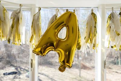 Close-up of yellow decorations hanging on window in building