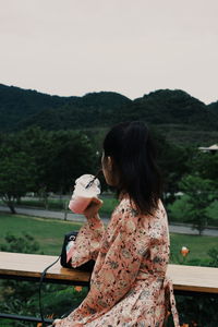 Side view of woman drinking milkshake outdoors