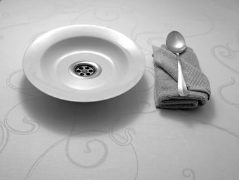 High angle view of antique plate by spoon and dish towel on table