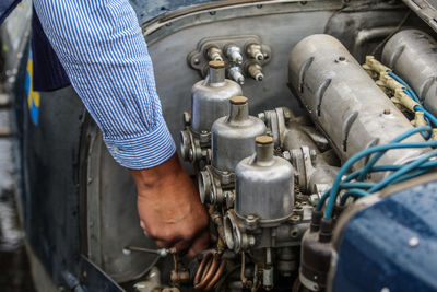 Cropped hand of man repairing car engine