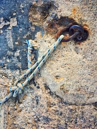 Close-up of rusty chain tied up on metal wall