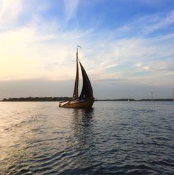 Sailboat sailing on sea against sky during sunset