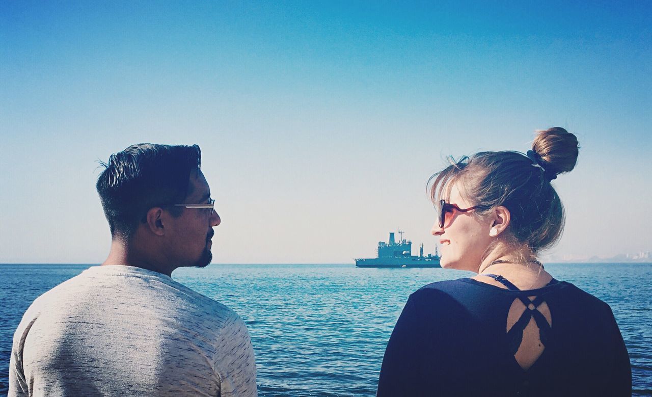 YOUNG COUPLE ON SHORE AGAINST CLEAR SKY