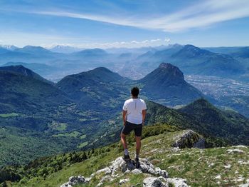 Rear view of man looking at mountains against sky