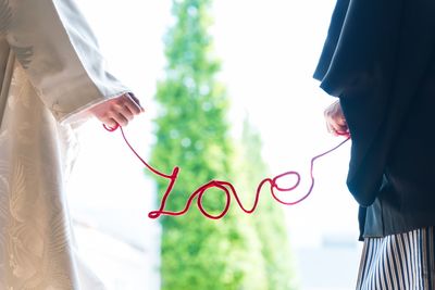 Midsection of couple holding love text while standing outdoors