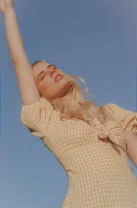 Low angle view of woman looking at blue sky