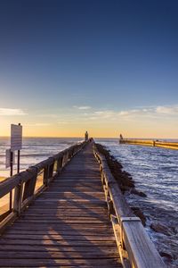 Pier over sea against sky during sunset