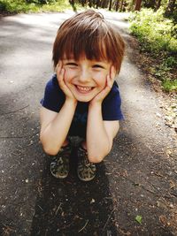 Portrait of smiling boy crouching on road