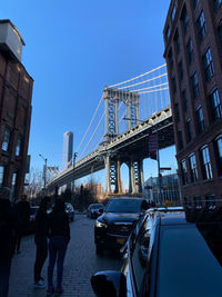 Vehicles on bridge against sky in city