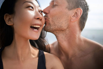 Young couple kissing and taking selfie on beach