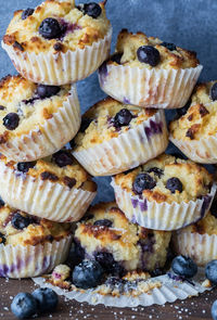 Freshly made blueberry muffins stacked high against a blue background.