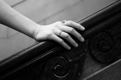 Close-up of hand with finger rings on wooden rail