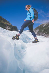 Low angle view of woman standing on snowcapped mountain