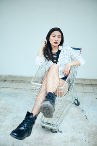 Portrait of young woman sitting in shopping cart