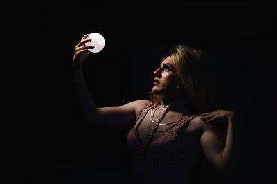 Portrait of woman holding hands over black background