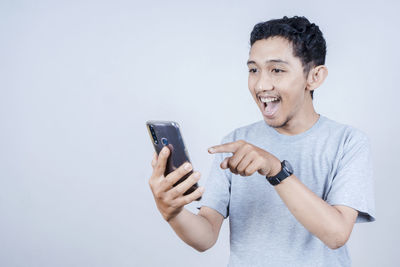 Young man using smart phone against white background