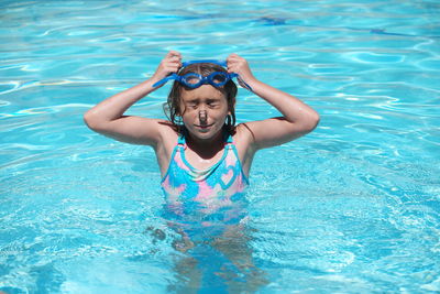 Girl wearing swimming goggles in pool