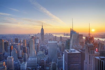 Modern buildings in city against sky during sunset