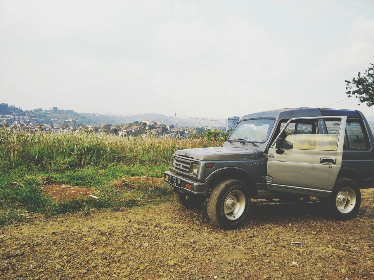 transportation, land vehicle, mode of transport, car, sky, field, clear sky, landscape, day, stationary, grass, outdoors, nature, copy space, tree, no people, parked, growth, tranquility, plant