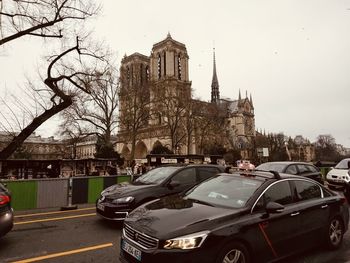 Cars on road amidst buildings against sky in city