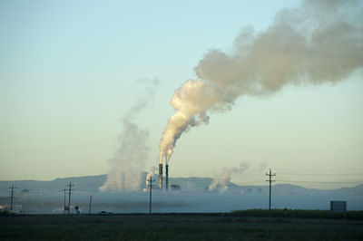 View of sugar processing plant behind fog or low clouds with stream piping up through smokestacks