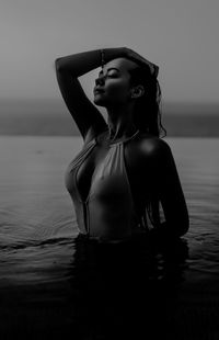 Woman looking away while standing at beach against sky